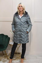 A model wearing a sage green padded coat with a detachable hood, paired with black pants.